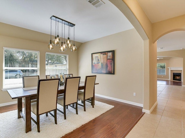 2829 Homecoming, Leander, TX 78641 - dining space with arched walkways, baseboards, wood finished floors, and a warm lit fireplace