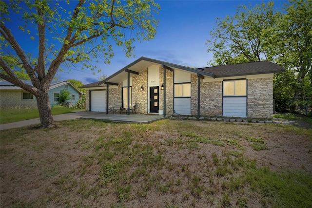 5307 Halmark Dr, Austin, TX 78723 - mid-century home featuring stone siding, an attached garage, concrete driveway, and a front lawn