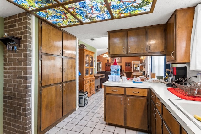 1304 Gatlinburg Dr, Pflugerville, TX 78660 - kitchen with light tile patterned floors, a peninsula, a sink, light countertops, and a textured ceiling