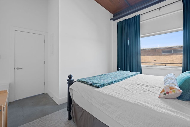 bedroom with baseboards, concrete flooring, and wooden ceiling