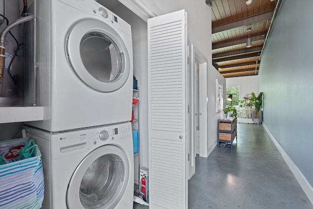 laundry room with stacked washing maching and dryer, wood ceiling, baseboards, and laundry area