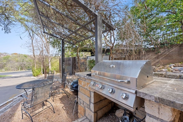 view of patio with grilling area, a pergola, and fence
