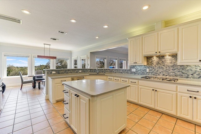 14415 Echo Blf, Austin, TX 78737 - kitchen with stainless steel gas cooktop, crown molding, a center island, light tile patterned floors, and light countertops