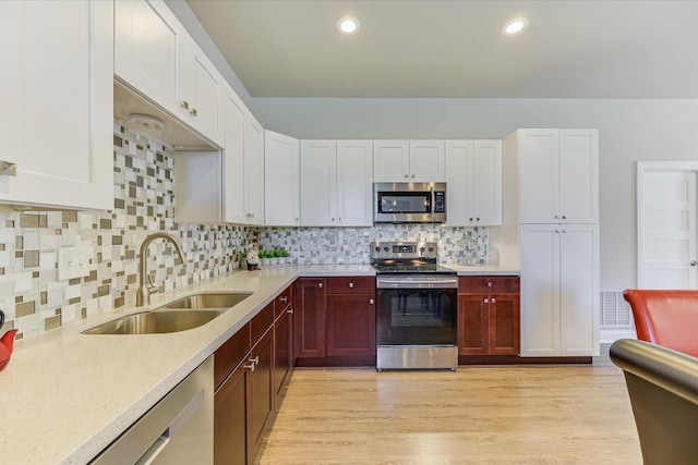 14415 Echo Blf, Austin, TX 78737 - kitchen with stainless steel appliances, light wood finished floors, tasteful backsplash, recessed lighting, and white cabinets