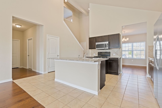 5825 Roderick Dr, Austin, TX 78724 - kitchen featuring stainless steel appliances, a chandelier, tasteful backsplash, baseboards, and light wood-type flooring