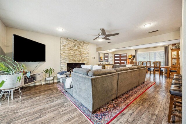2402 Stevens Cv, Austin, TX 78723 - living room with wood finished floors, a ceiling fan, a stone fireplace, and recessed lighting