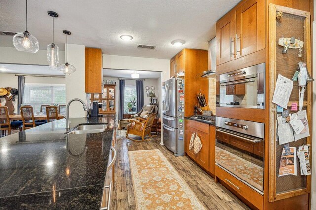 2402 Stevens Cv, Austin, TX 78723 - kitchen with freestanding refrigerator, brown cabinetry, plenty of natural light, fridge, and a textured ceiling