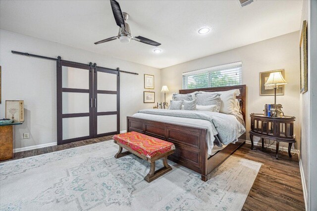2402 Stevens Cv, Austin, TX 78723 - bedroom with a barn door, dark wood finished floors, recessed lighting, and ceiling fan