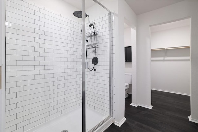 12024 Roving Pass, Elgin, TX 78621 - bathroom featuring a shower stall, toilet, wood finished floors, a walk in closet, and baseboards