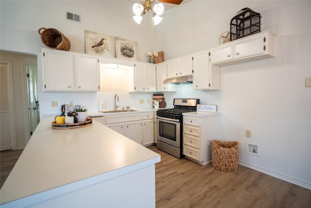 1510 Prather St, Taylor, TX 76574 - kitchen featuring light wood-type flooring, stainless steel gas stove, a sink, under cabinet range hood, and light countertops