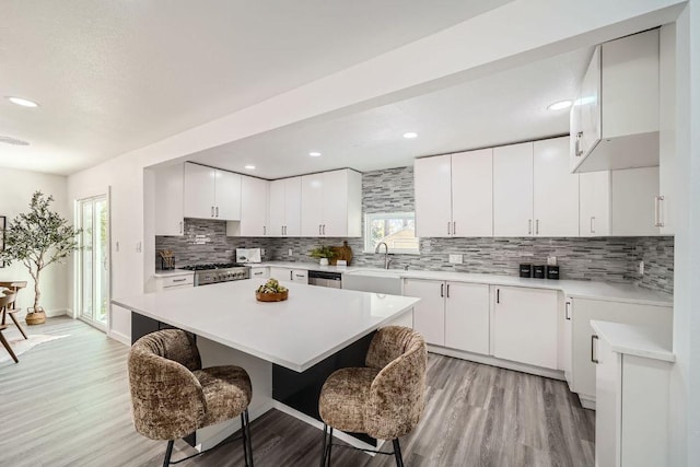 5510 Coventry Ln, Austin, TX 78723 - kitchen with a breakfast bar, backsplash, light wood-type flooring, range, and a sink