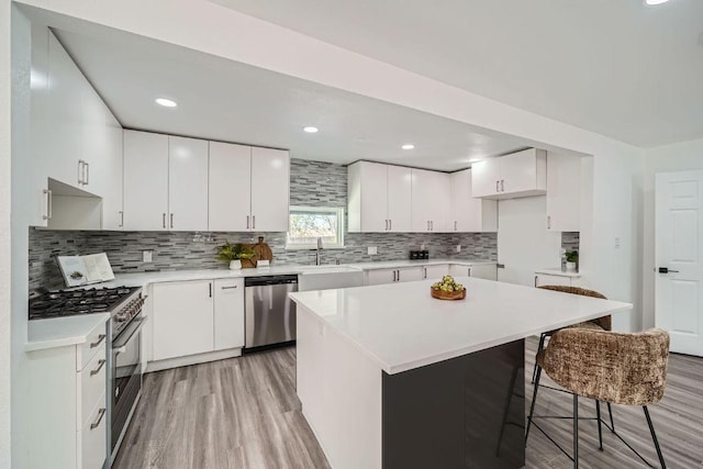 5510 Coventry Ln, Austin, TX 78723 - kitchen featuring appliances with stainless steel finishes, light wood-style flooring, a kitchen bar, tasteful backsplash, and recessed lighting