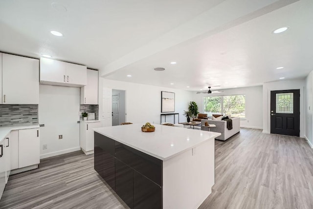 5510 Coventry Ln, Austin, TX 78723 - kitchen featuring backsplash, light countertops, white cabinets, light wood-style floors, and a center island