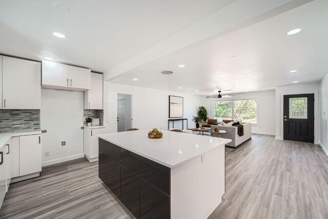 5510 Coventry Ln, Austin, TX 78723 - kitchen with decorative backsplash, light countertops, white cabinets, light wood-type flooring, and a kitchen island