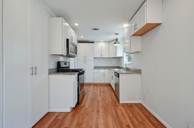 5907 Glenhollow Path, Austin, TX 78745 - kitchen with appliances with stainless steel finishes, a sink, light wood-type flooring, backsplash, and white cabinetry