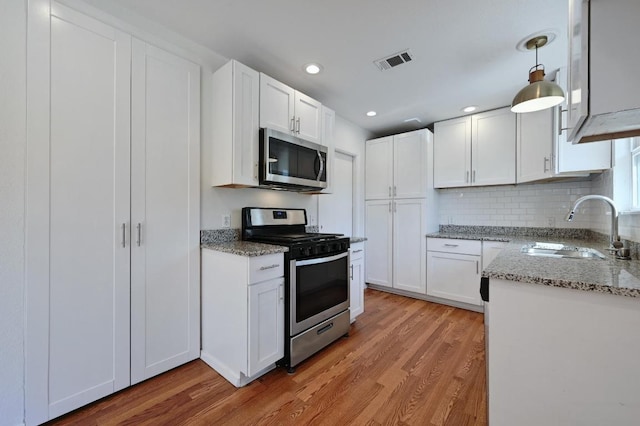 5907 Glenhollow Path, Austin, TX 78745 - kitchen with appliances with stainless steel finishes, a sink, light wood-type flooring, white cabinets, and light stone counters