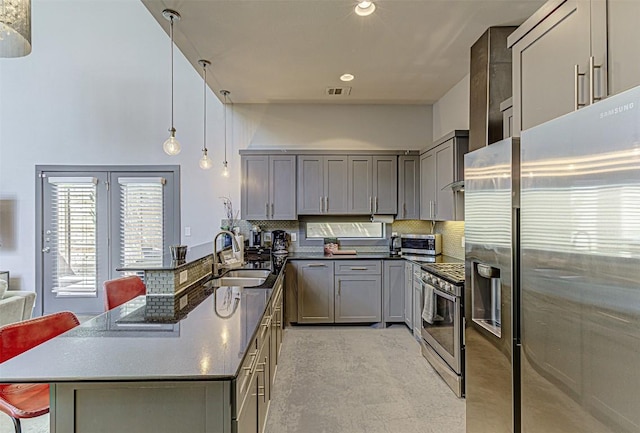2612 Hidalgo St, Austin, TX 78702 - kitchen featuring stainless steel appliances, gray cabinets, dark countertops, decorative backsplash, and a high ceiling