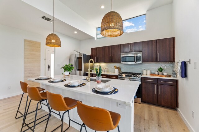 5809 Toscana Ave, Austin, TX 78724 - kitchen featuring stainless steel appliances, a sink, decorative backsplash, light wood finished floors, and light countertops