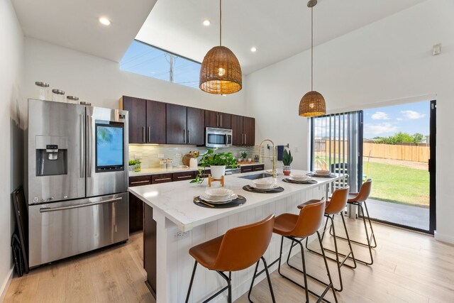 5809 Toscana Ave, Austin, TX 78724 - kitchen featuring stainless steel appliances, a sink, dark brown cabinets, backsplash, and a kitchen breakfast bar