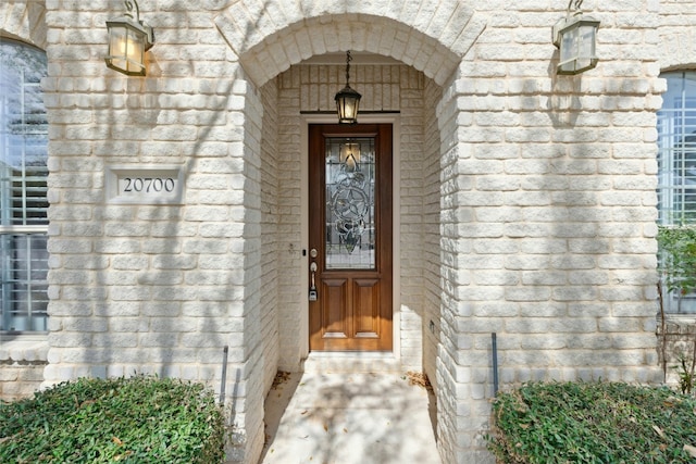 view of exterior entry featuring brick siding and stone siding