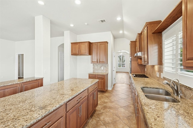 kitchen featuring plenty of natural light, a sink, arched walkways, and gas stovetop