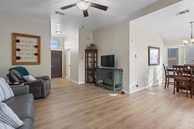 living room featuring baseboards, visible vents, light wood finished floors, and ceiling fan with notable chandelier
