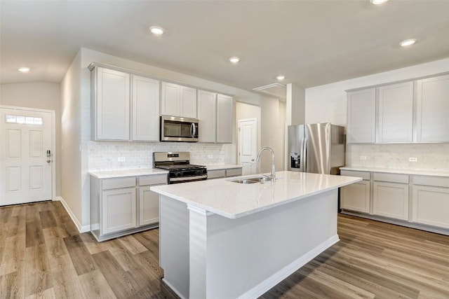 152 Greenway Ln, Georgetown, TX 78628 - kitchen with appliances with stainless steel finishes, light wood-style flooring, backsplash, light countertops, and a kitchen island with sink