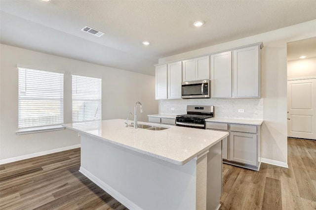 152 Greenway Ln, Georgetown, TX 78628 - kitchen featuring stainless steel appliances, decorative backsplash, light wood-style flooring, an island with sink, and white cabinetry