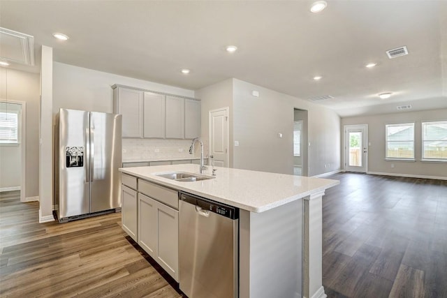 152 Greenway Ln, Georgetown, TX 78628 - kitchen featuring appliances with stainless steel finishes, wood finished floors, a kitchen island with sink, backsplash, and recessed lighting