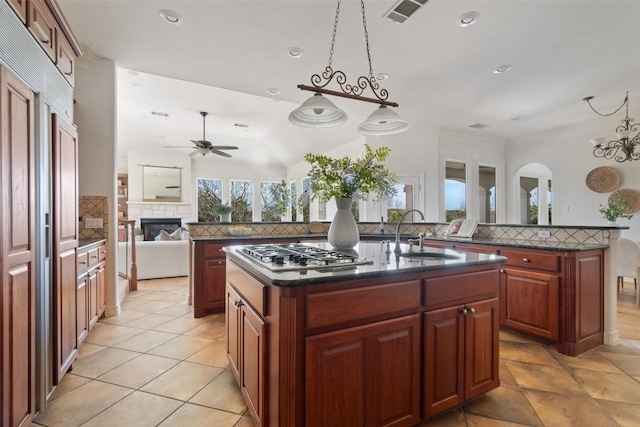 kitchen featuring backsplash, visible vents, a sink, a center island with sink, and stainless steel gas cooktop