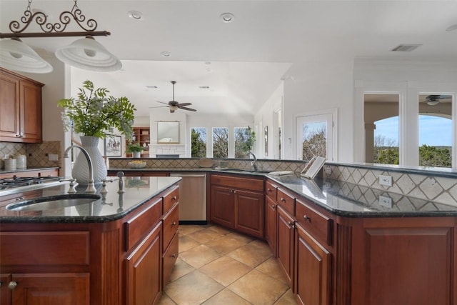 kitchen with ceiling fan, stainless steel dishwasher, an island with sink, and a sink