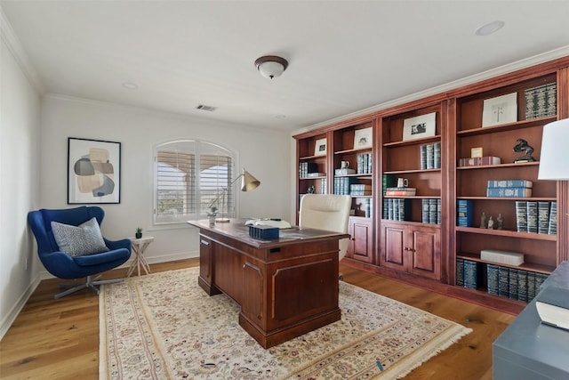 office featuring baseboards, light wood-style flooring, visible vents, and crown molding