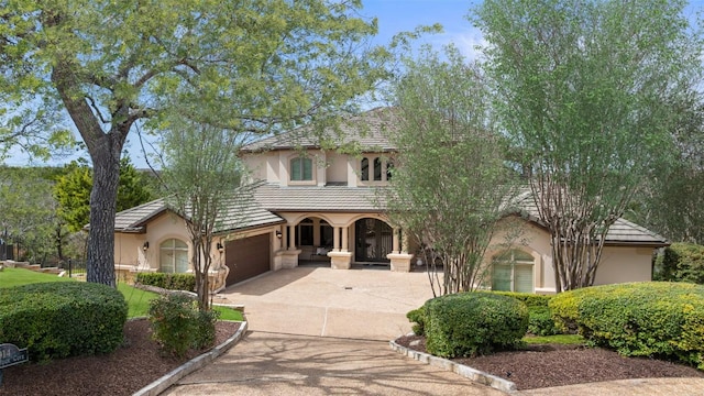 mediterranean / spanish-style home featuring a tile roof, driveway, and stucco siding