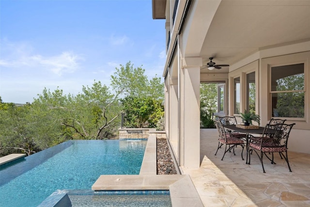 view of pool with outdoor dining area, an infinity pool, a patio area, and ceiling fan