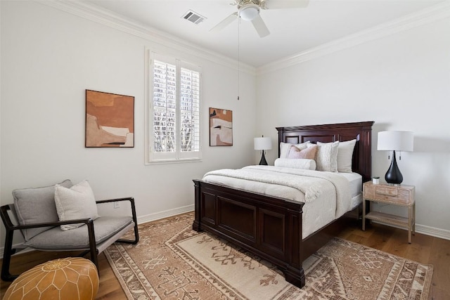 bedroom featuring baseboards, ornamental molding, light wood finished floors, and visible vents