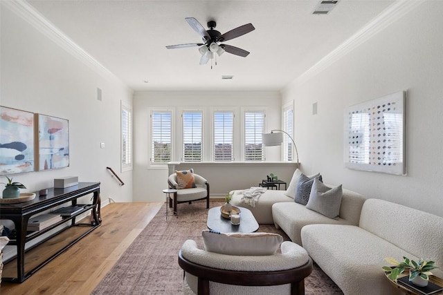 living room featuring wood finished floors, visible vents, ornamental molding, and a ceiling fan