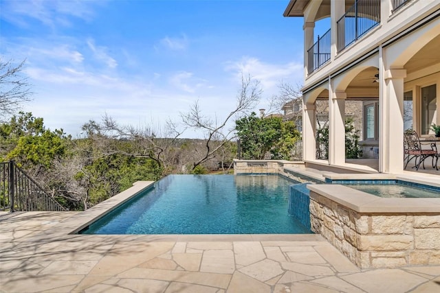 view of pool with a patio area, a ceiling fan, an infinity pool, and an in ground hot tub