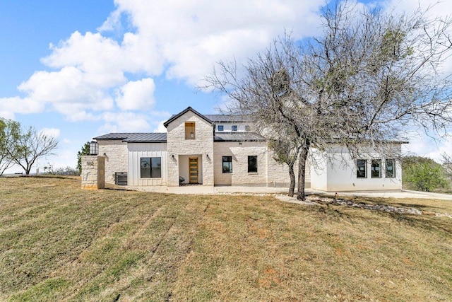 102 Mountain Home Rd, Horseshoe Bay, TX 78657 - rear view of house featuring a standing seam roof, stone siding, metal roof, a lawn, and board and batten siding