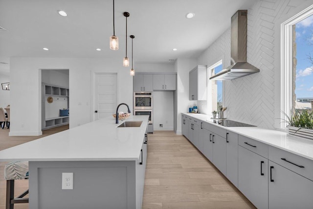 102 Mountain Home Rd, Horseshoe Bay, TX 78657 - kitchen with wall chimney exhaust hood, a sink, double oven, light wood finished floors, and black electric stovetop