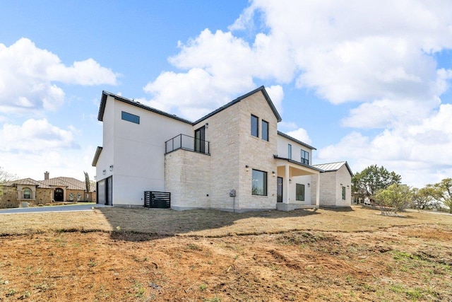 102 Mountain Home Rd, Horseshoe Bay, TX 78657 - rear view of property featuring a balcony, a standing seam roof, an attached garage, stone siding, and metal roof