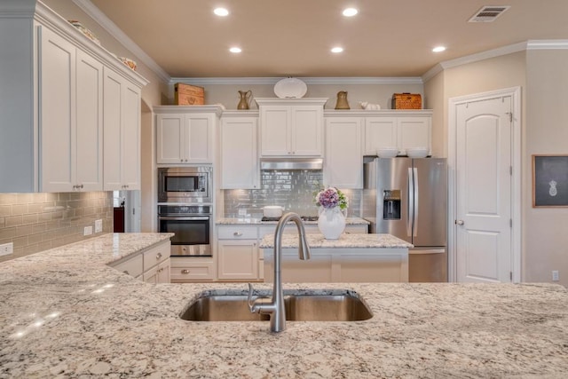 3204 Venezia Vw, Leander, TX 78641 - kitchen with stainless steel appliances, under cabinet range hood, white cabinets, backsplash, and recessed lighting