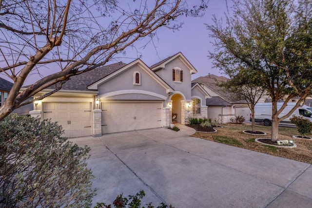 3204 Venezia Vw, Leander, TX 78641 - view of front facade with stucco siding, concrete driveway, a garage, roof with shingles, and stone siding