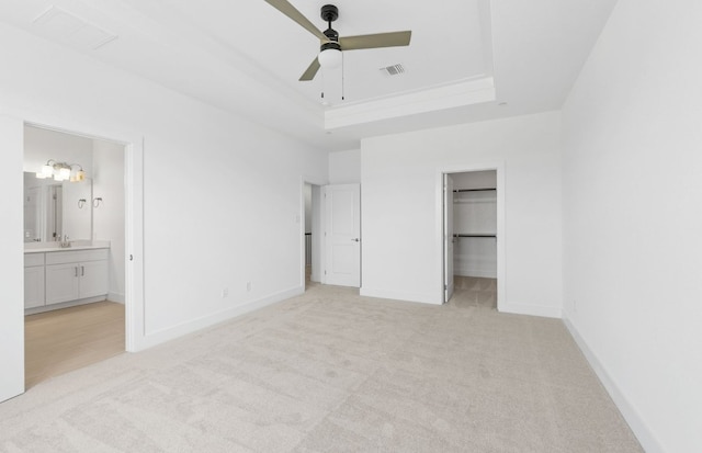 1955 Settlers Glen Dr Unit 5402, Round Rock, TX 78665 - unfurnished bedroom featuring light colored carpet, a tray ceiling, a walk in closet, baseboards, and connected bathroom