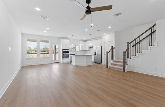1955 Settlers Glen Dr Unit 5402, Round Rock, TX 78665 - unfurnished living room featuring healthy amount of natural light, light wood finished floors, baseboards, stairs, and recessed lighting