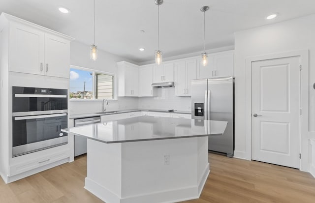 1955 Settlers Glen Dr Unit 5402, Round Rock, TX 78665 - kitchen featuring appliances with stainless steel finishes, under cabinet range hood, a center island, white cabinetry, and backsplash