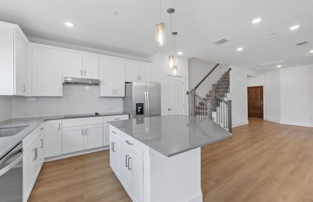 1955 Settlers Glen Dr Unit 5402, Round Rock, TX 78665 - kitchen featuring stainless steel appliances, under cabinet range hood, decorative backsplash, a center island, and light wood finished floors