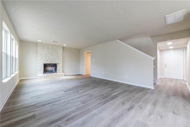 3901 Skipton Dr, Austin, TX 78727 - unfurnished living room featuring wood finished floors, a fireplace, recessed lighting, a textured ceiling, and stairs