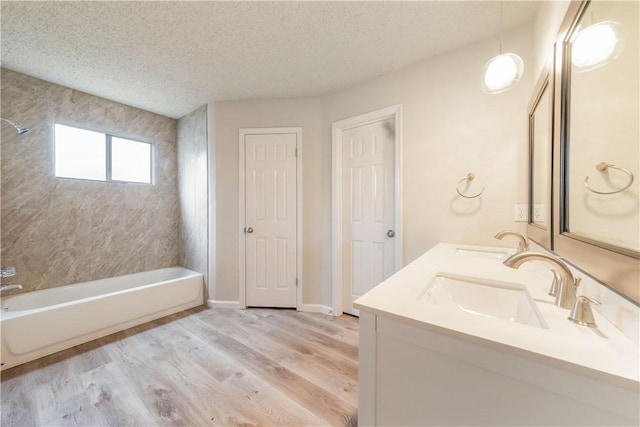 3901 Skipton Dr, Austin, TX 78727 - bathroom featuring wood finished floors, a textured ceiling, double vanity, and bathing tub / shower combination