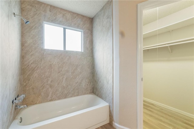 3901 Skipton Dr, Austin, TX 78727 - full bathroom featuring tub / shower combination, wood finished floors, a walk in closet, and a textured ceiling