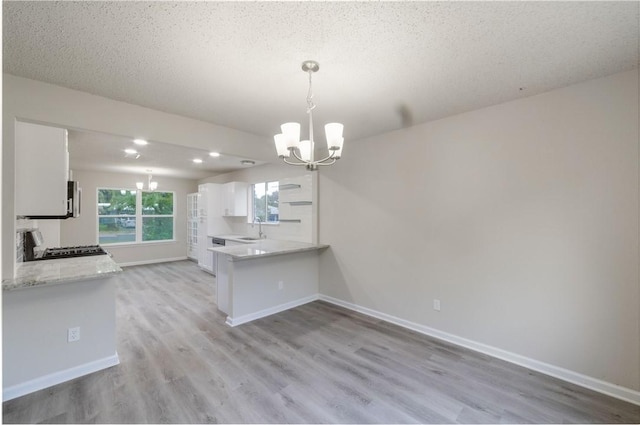 3901 Skipton Dr, Austin, TX 78727 - kitchen featuring a chandelier, white cabinets, light wood-type flooring, light countertops, and a peninsula